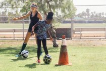 Schoolgirls doing dribbling soccer ball practice on school sports field — Stock Photo