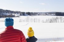 Rückansicht von Mann und Sohn mit Blick auf die Winterlandschaft — Stockfoto