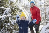 Hombre e hijo caminando por el bosque nevado - foto de stock
