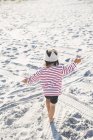 Вид сзади на маленькую девочку, играющую на пляже — стоковое фото