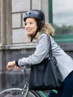 Mujer adulta sentada en bicicleta, con casco de seguridad - foto de stock