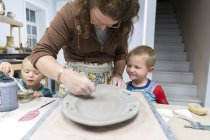 Mulher com filhos pintando em prato de barro — Fotografia de Stock