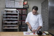 Chef dans la cuisine commerciale tranchant aubergine — Photo de stock
