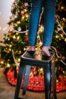 Child on stool reaching up to decorate Christmas tree — Stock Photo