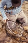 Fischer kniet mit gefangenem Netzfisch im Fluss, Mozirje, Brezovica, Slowenien — Stockfoto