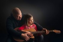 Padre insegnare figlia a suonare la chitarra — Foto stock