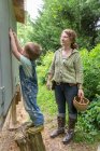 Mother and son collecting eggs from chicken coop — Stock Photo