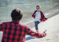 Father and son on beach, son running towards father — Stock Photo