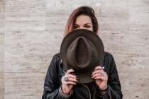 Portrait of woman hiding face behind hat — Stock Photo