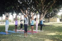 Colegialas practicando yoga posan en el campo deportivo de la escuela - foto de stock