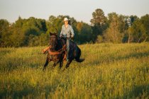 Jovem mulher equitação cavalo no campo — Fotografia de Stock