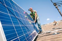 Рабочий, устанавливающий солнечные панели на крыше дома — стоковое фото