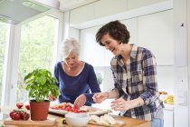 Mother and grown daughter at home, preparing food together — Stock Photo