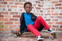 Ritratto di giovane ragazzo seduto su skateboard — Foto stock