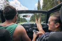 Young woman with smartphone driving on road trip with boyfriend, Breckenridge, Colorado, USA — Stock Photo