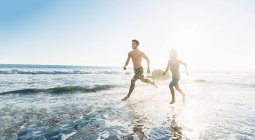 Brothers running on El Matador Beach, Malibú, Estados Unidos - foto de stock