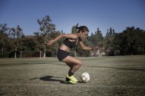 Mujer joven en campo de fútbol jugando fútbol - foto de stock
