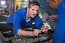 Автомобільна механіка оглядає автомобільний двигун у ремонті гаража — стокове фото