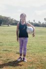 Portrait d'une écolière tenant un ballon de soccer sur un terrain de sport scolaire — Photo de stock