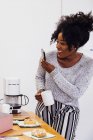 Mujer sosteniendo la taza de café y tomando fotos en el teléfono inteligente - foto de stock