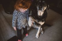 Молодая девушка, стоящая рядом с собакой, держа собачью лапу — стоковое фото