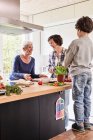 Young boy, mother and grandmother making pizza together in kitchen — Stock Photo