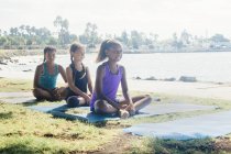 Три школьницы практикующие йогу позируют на школьной спортивной площадке — стоковое фото