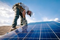 Arbeiter, der Sonnenkollektoren auf dem Dach des Hauses installiert, niedriger Blickwinkel — Stockfoto