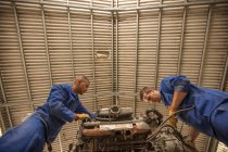 Niedriger Blickwinkel der Kfz-Mechaniker bei der Inspektion des Automotors in der Werkstatt — Stockfoto