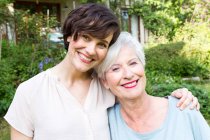 Portrait of senior woman with grown daughter, outdoors, smiling — Stock Photo