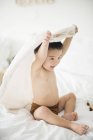 Menino com toalha com capuz na cama — Fotografia de Stock