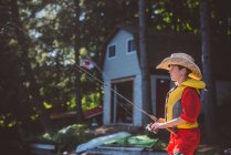 Boy in cowboy hat fishing from lakeside — Stock Photo