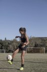 Jeune femme sur le terrain de football avec le football — Photo de stock