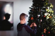 Vista lateral do menino colocando decorações de Natal — Fotografia de Stock