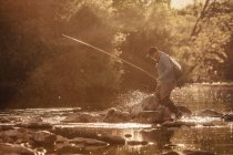 Pescador pisando el tobillo profundamente en el río soleado, Mozirje, Brezovica, Eslovenia - foto de stock
