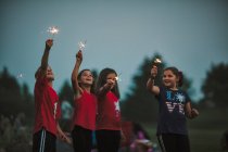 Group of friends, arms raised holding sparklers — Stock Photo