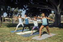 Colegialas practicando yoga guerrero posan en el campo deportivo de la escuela - foto de stock