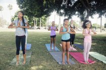 Niñas y adolescentes practicando yoga pose de montaña en el campo de juego de la escuela - foto de stock