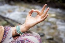 Close up of young woman meditating by river — Stock Photo