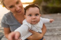 Portrait of mother carrying baby daughter on lake pier — Stock Photo