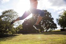 Young woman leaping mid air and training in park — Stock Photo