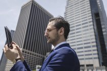 Молодий бізнесмен дивиться на цифровий планшет на відкритому повітрі — стокове фото
