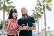 Couple hipster mature dans un parc regardant un smartphone, Valencia, Espagne — Photo de stock