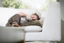 Bebê menina bebendo de garrafa de leite no sofá — Fotografia de Stock