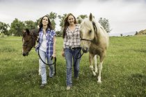 Молодая женщина и ее сестра ведущие лошади в поле, Бриджер, Монтана, США — стоковое фото