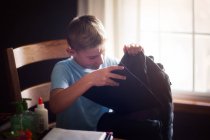 Мальчик упаковывает рюкзак со школьными принадлежностями — стоковое фото