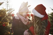 Girl and mother in christmas tree forest wearing red noses — Stock Photo