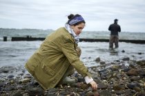 Giovane donna accovacciata sulla spiaggia mentre pesca fidanzato — Foto stock