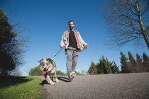 Vista a basso angolo dell'uomo che cammina con il cane nel parco cittadino — Foto stock