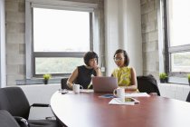 Two women using laptop at meeting room table — Stock Photo